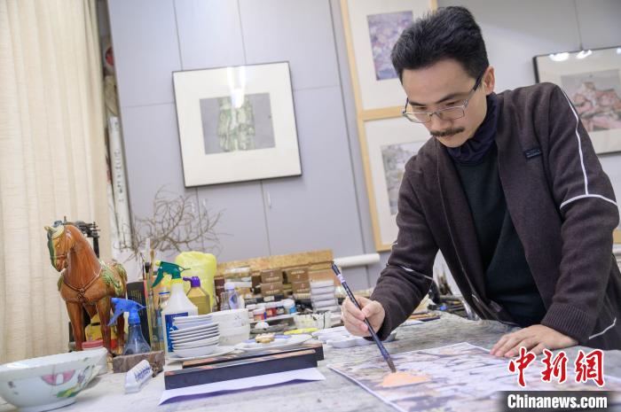 图为翁志承在为抗疫系列的画作进行润色。　李南轩 摄